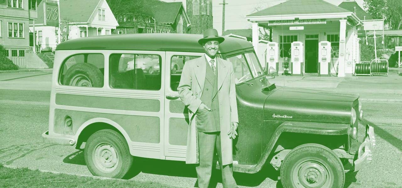 Old image of a man standing in front of his car.