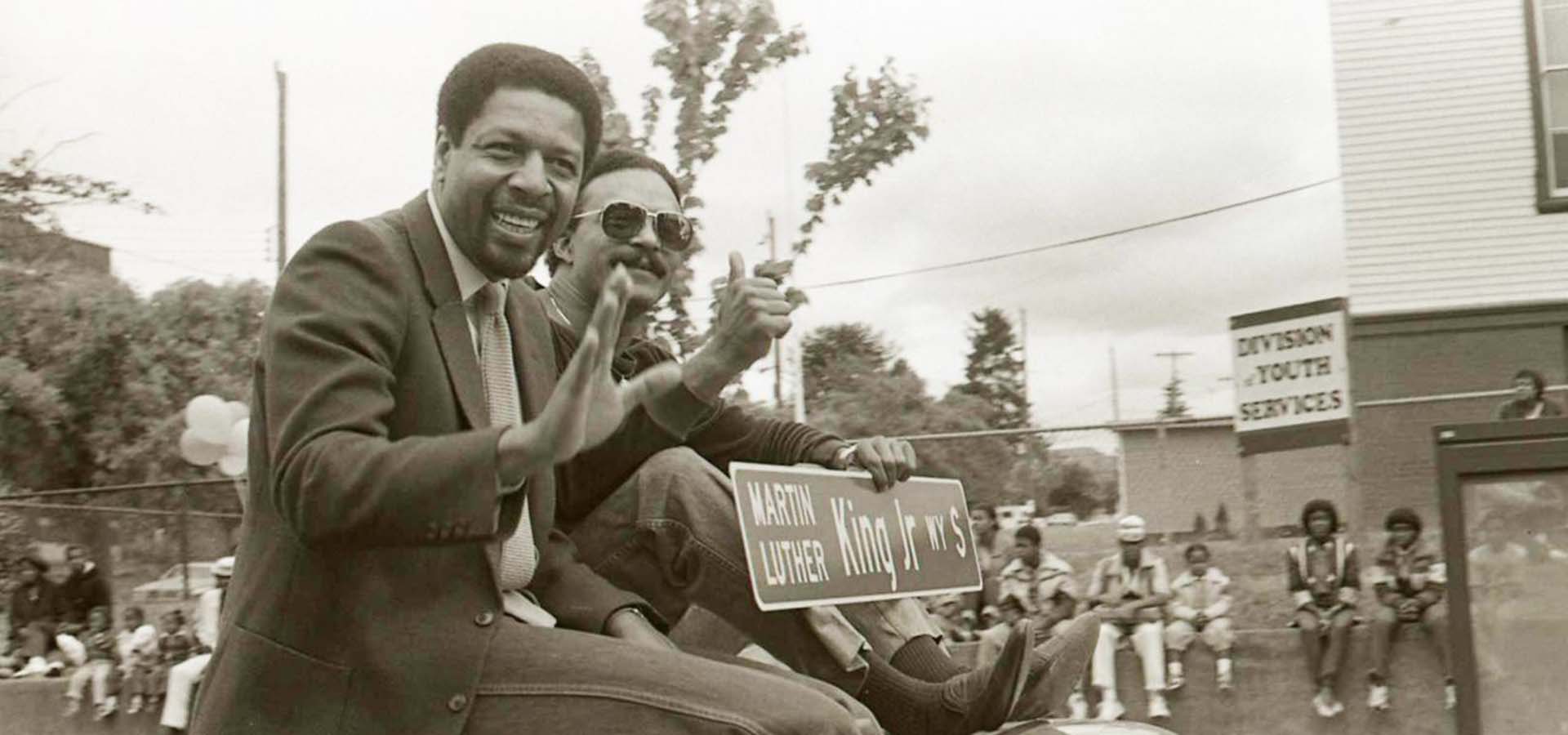 African-American men waving to a crowd.