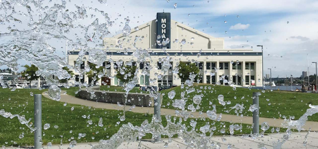 Photograph of MOHAI with water spray from a walkway fountain in the foreground.