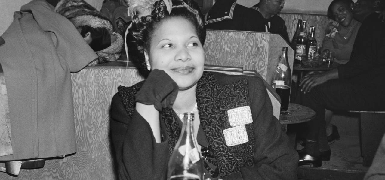 1940's woman smiling while sitting at a table.