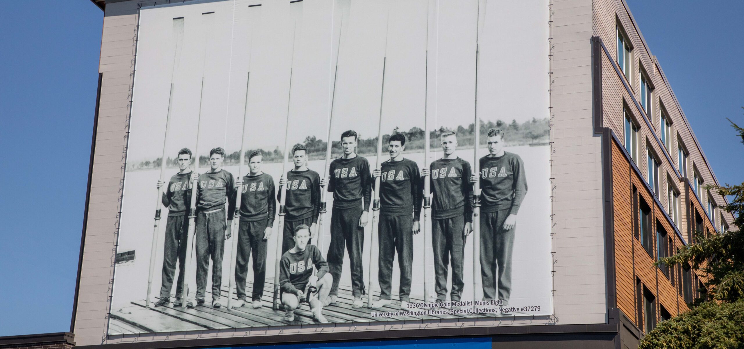 Exterior of a building displaying a full-size mural of 1936 gold medal-winning University of Washington rowing team.