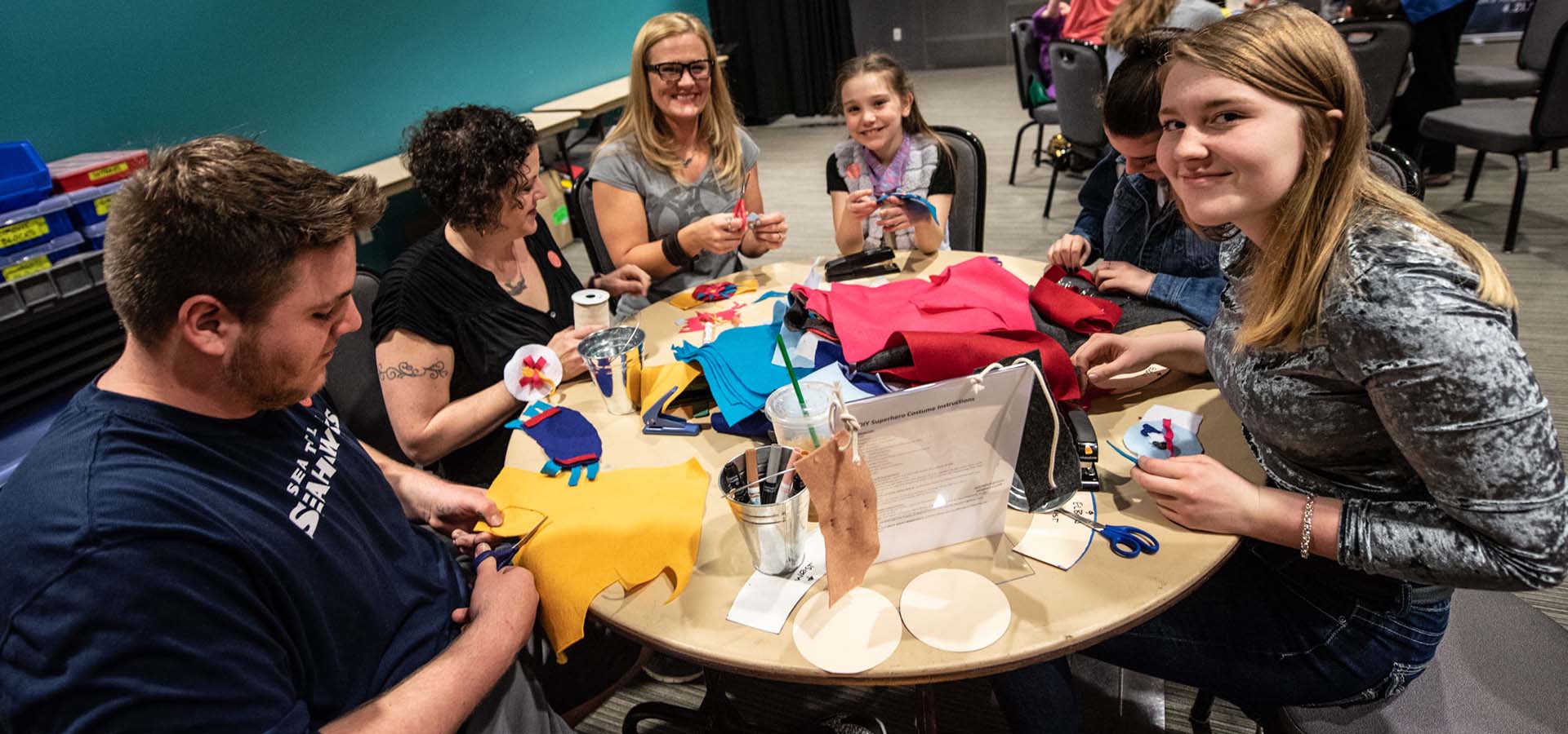 Group of parents and kids at a table working on a craft project.