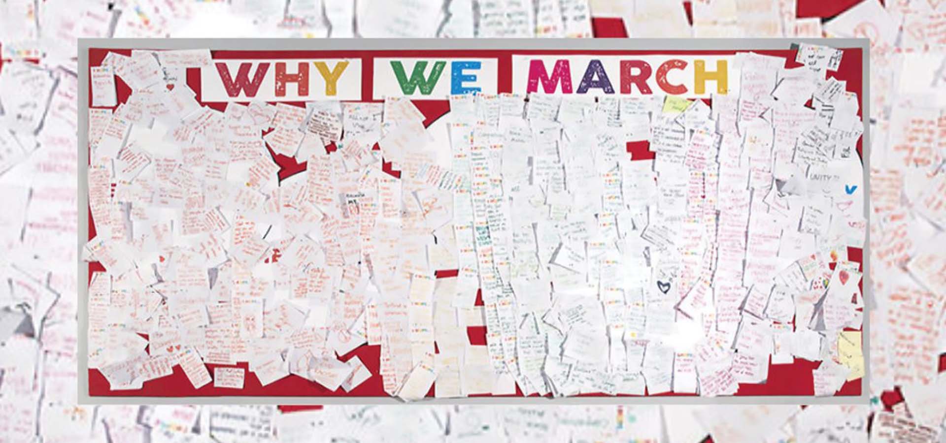 Bulletin board with hundreds of notes posted on it under a heading reading 'Why We March."