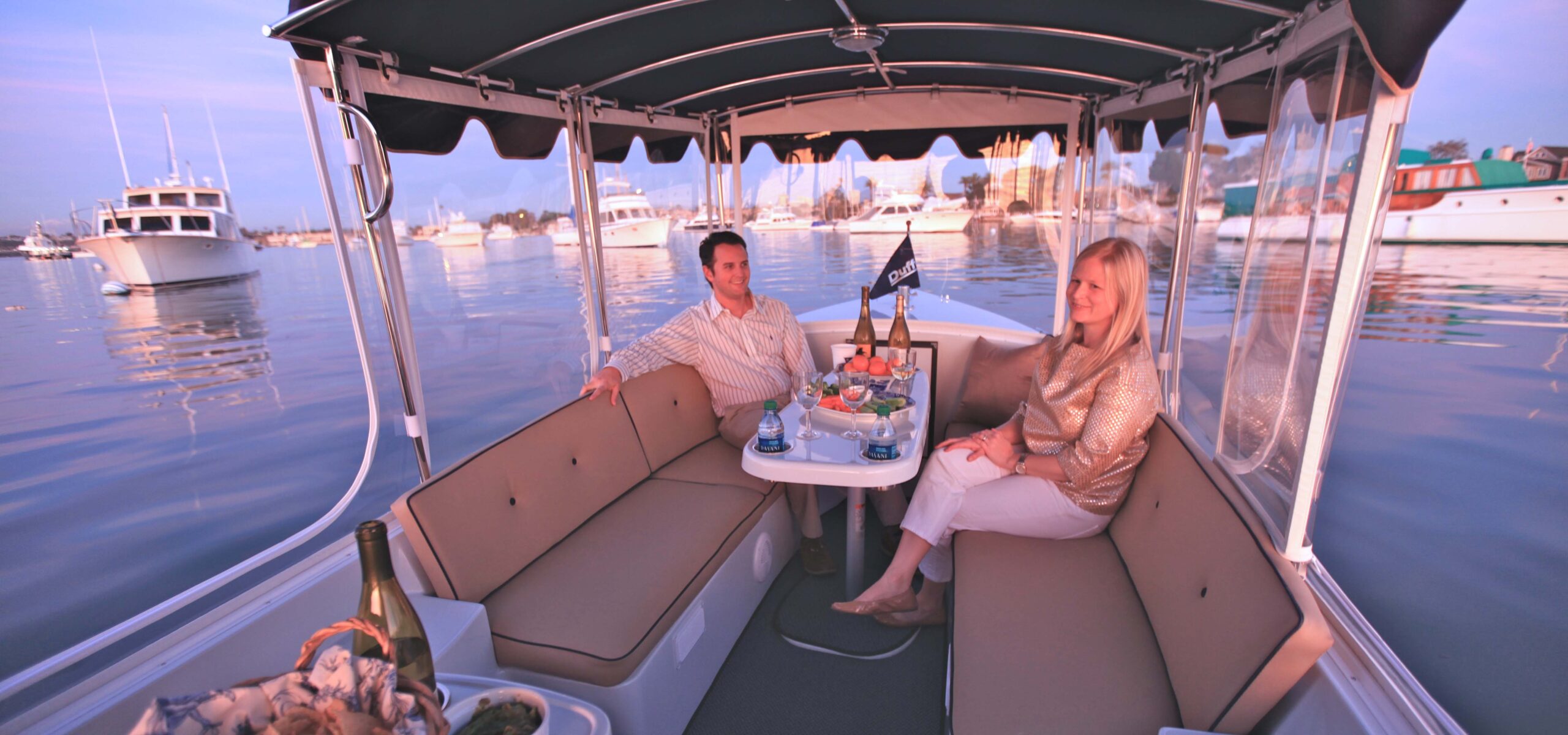 Two people enjoying a sunset picnic dinner on a Seattle Electric Boat rental.