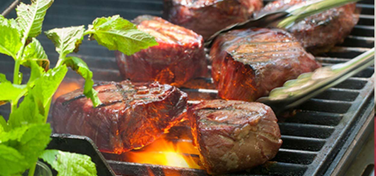 Steaks being cooked on a grill.