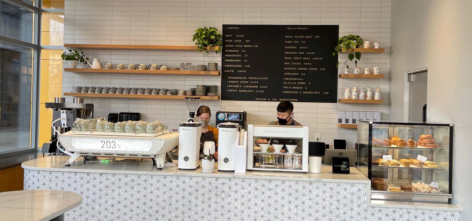 Two people working behind a coffee counter.