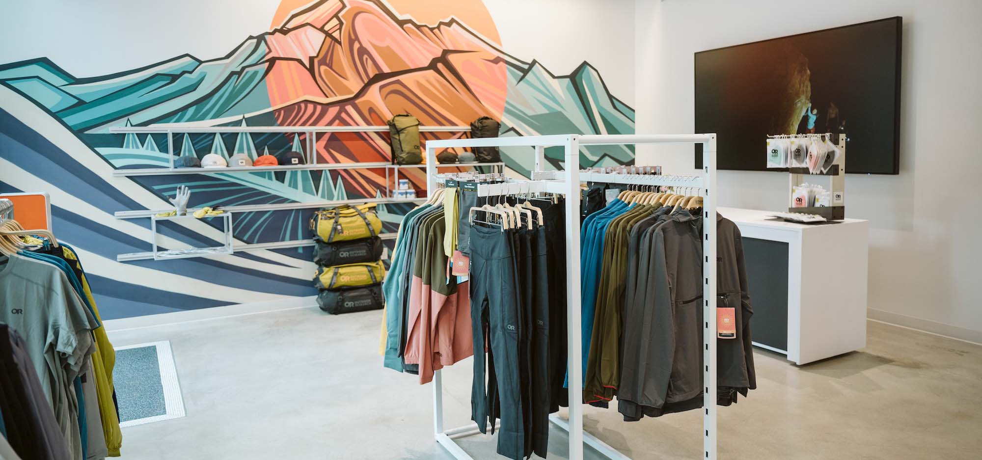 Inside an outdoor clothing shop with a mountain mural in the background on the wall.