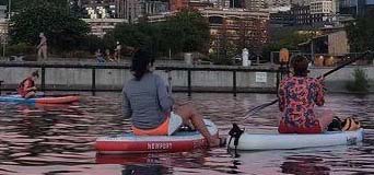 Women sitting on paddle boards on a lake.