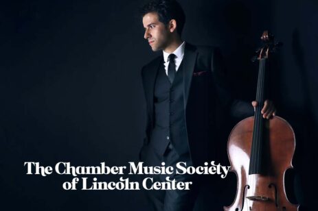Man in a black suit holding his cello.