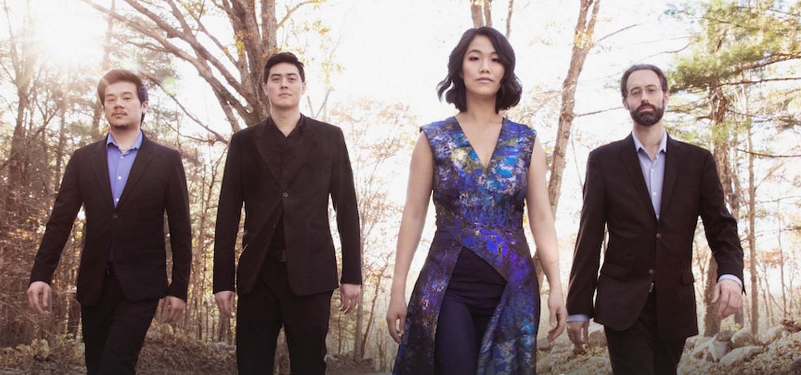 A classical quartet group posing in a forest.