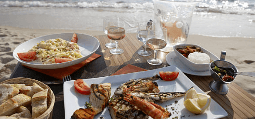 A seafood and wine dinner served on a beach.