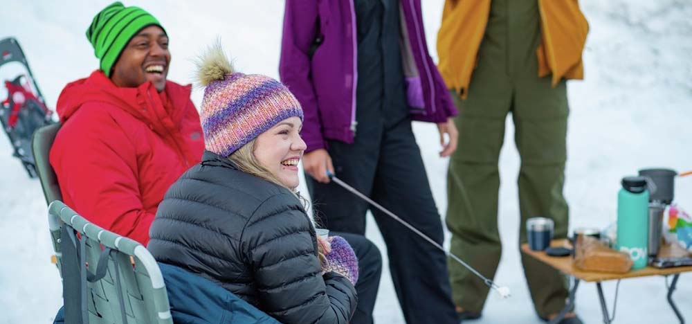 People roasting marshmallows while winter camping.