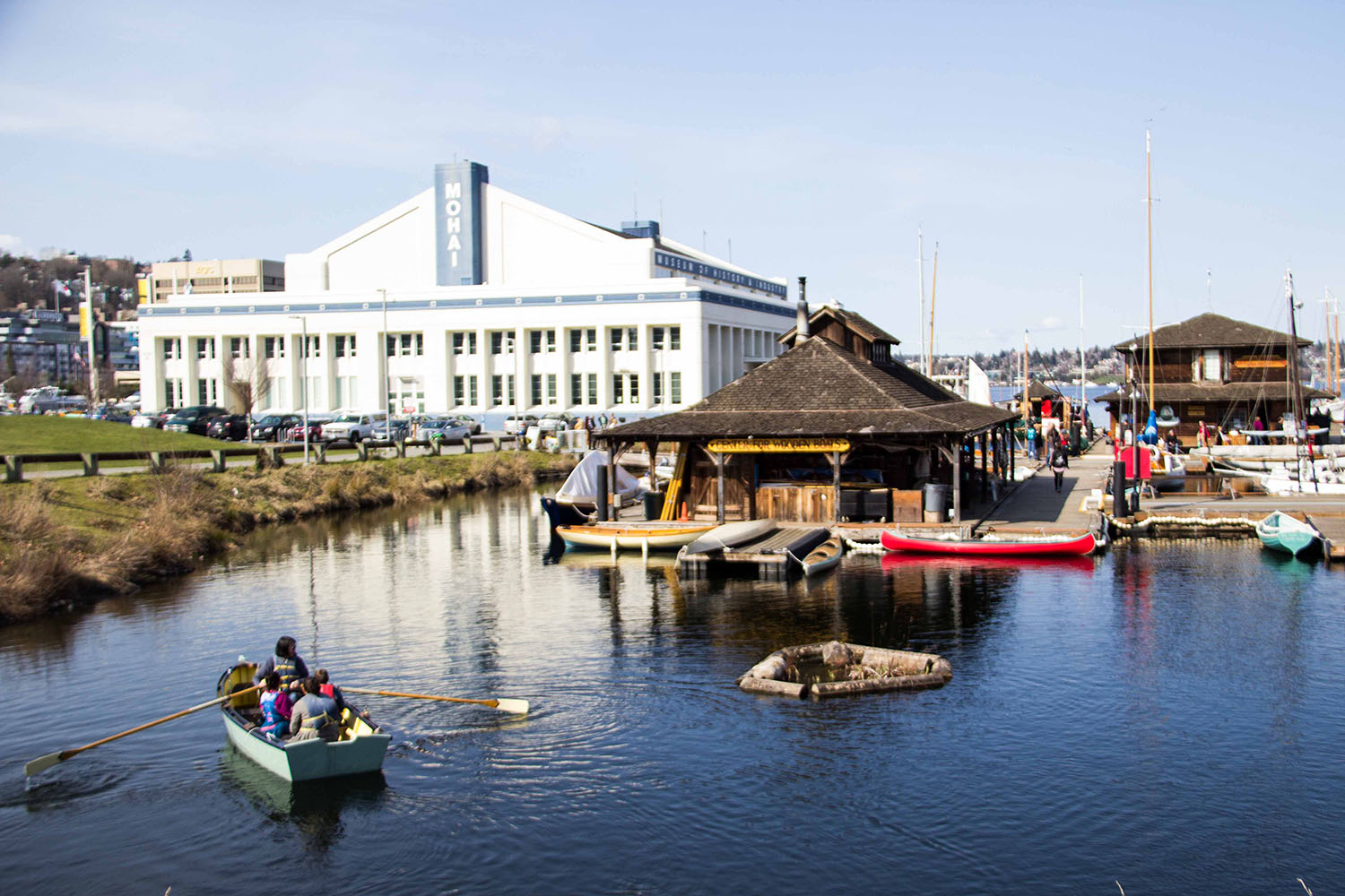 people in boat in front of MOHAI and The Center for Wooden Boats