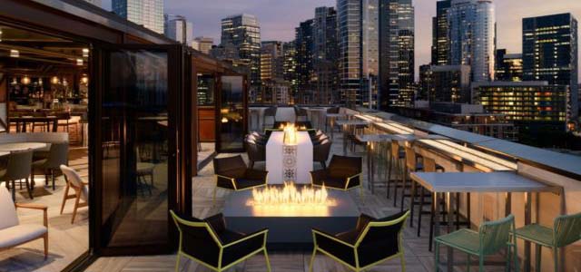 Outdoor rooftop lounge with fire pit table and chairs.