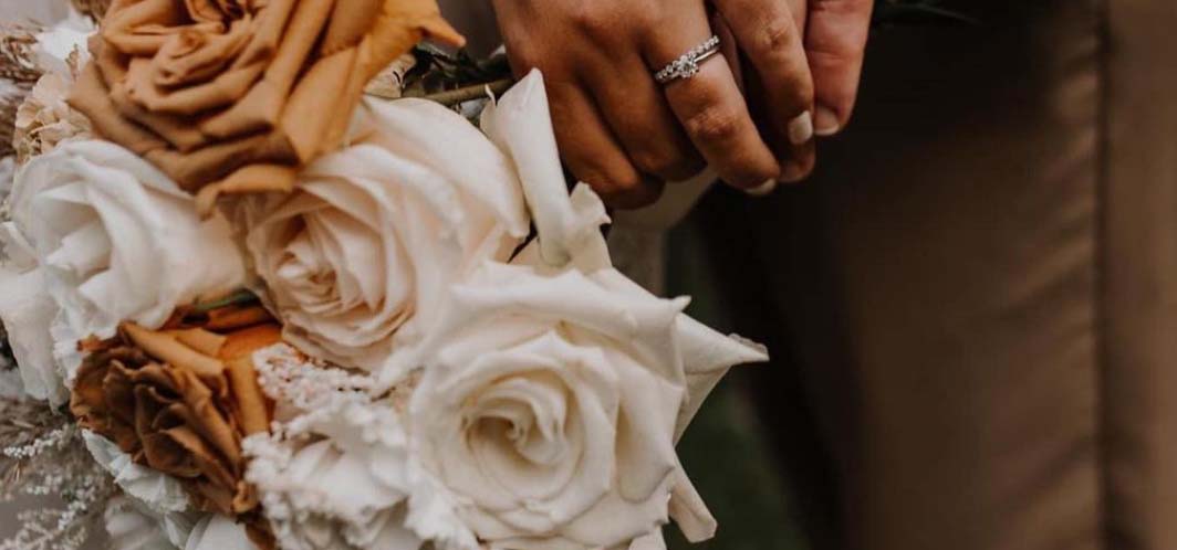 Bride and groom holding hands and holding a bouquet.