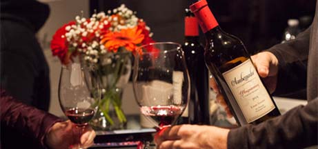 Wine glasses filled with red wine being toasted.