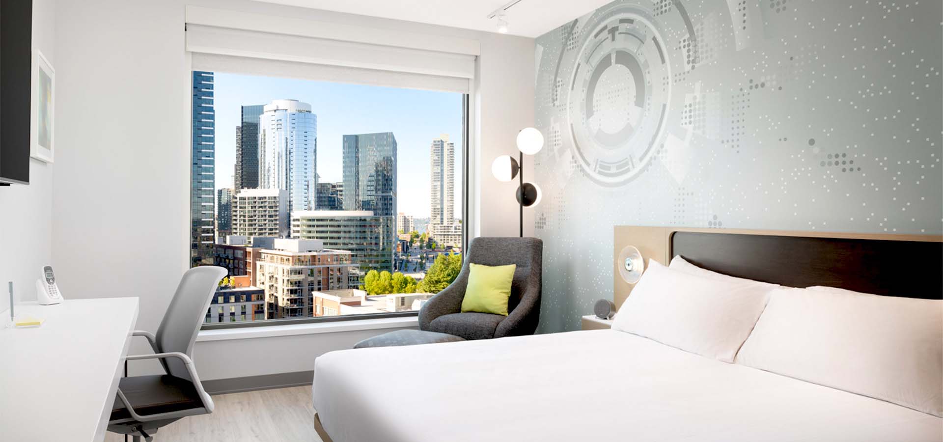 Graphic rendering of a hotel room interior with a view of a downtown city.