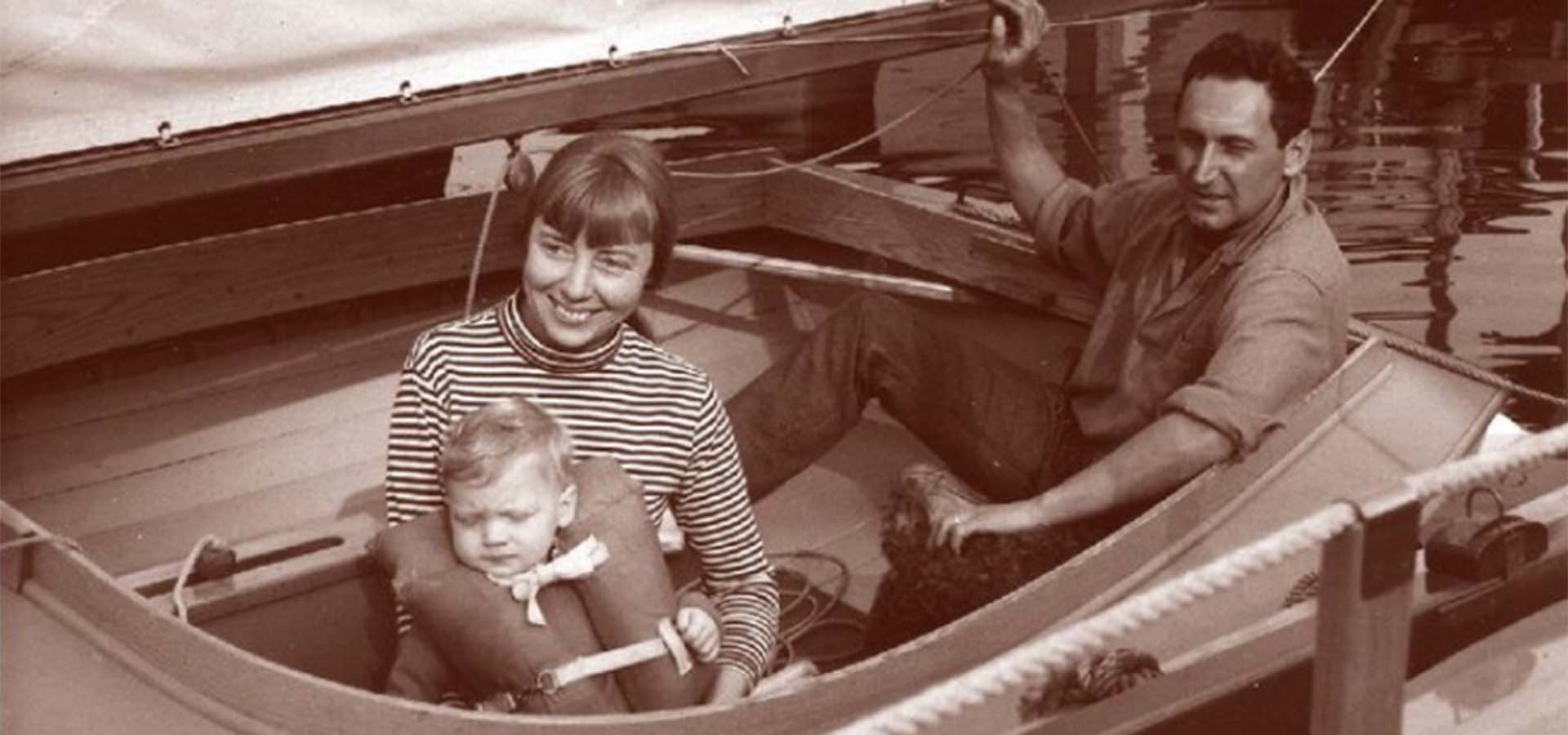 Old photo of a small family in a personal sailboat.
