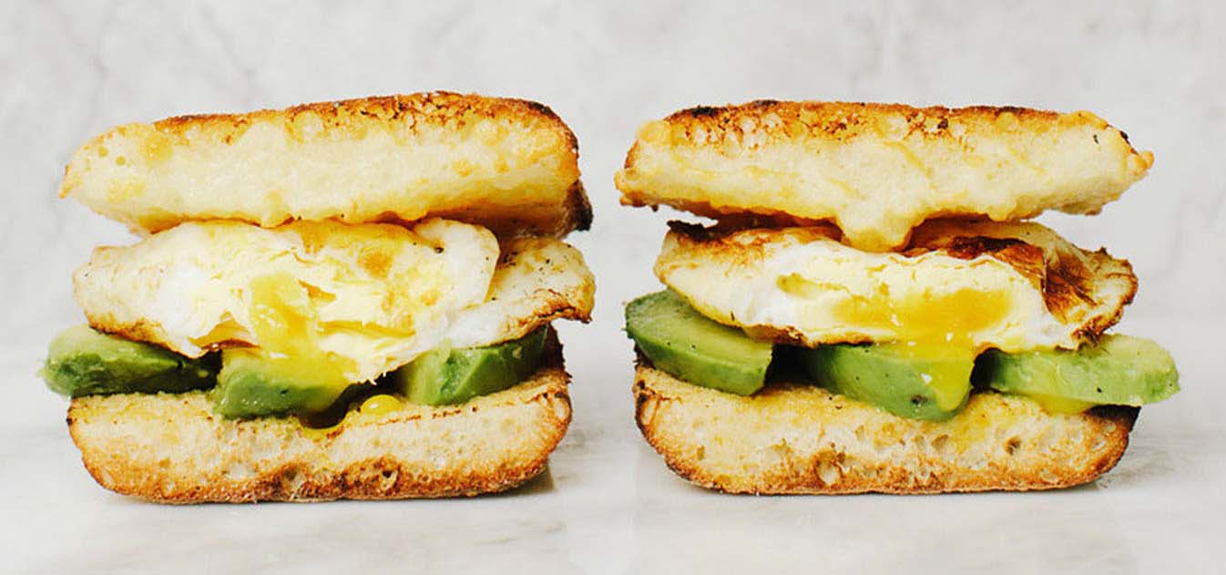 Egg and avocado breakfast sandwich on an English muffin, cut in half.