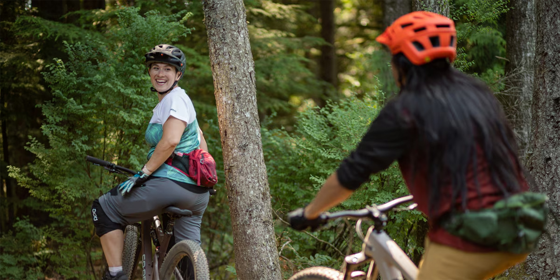 two people riding bikes through forest