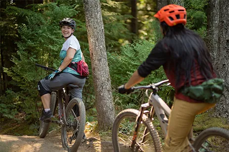 two people riding bikes through forest