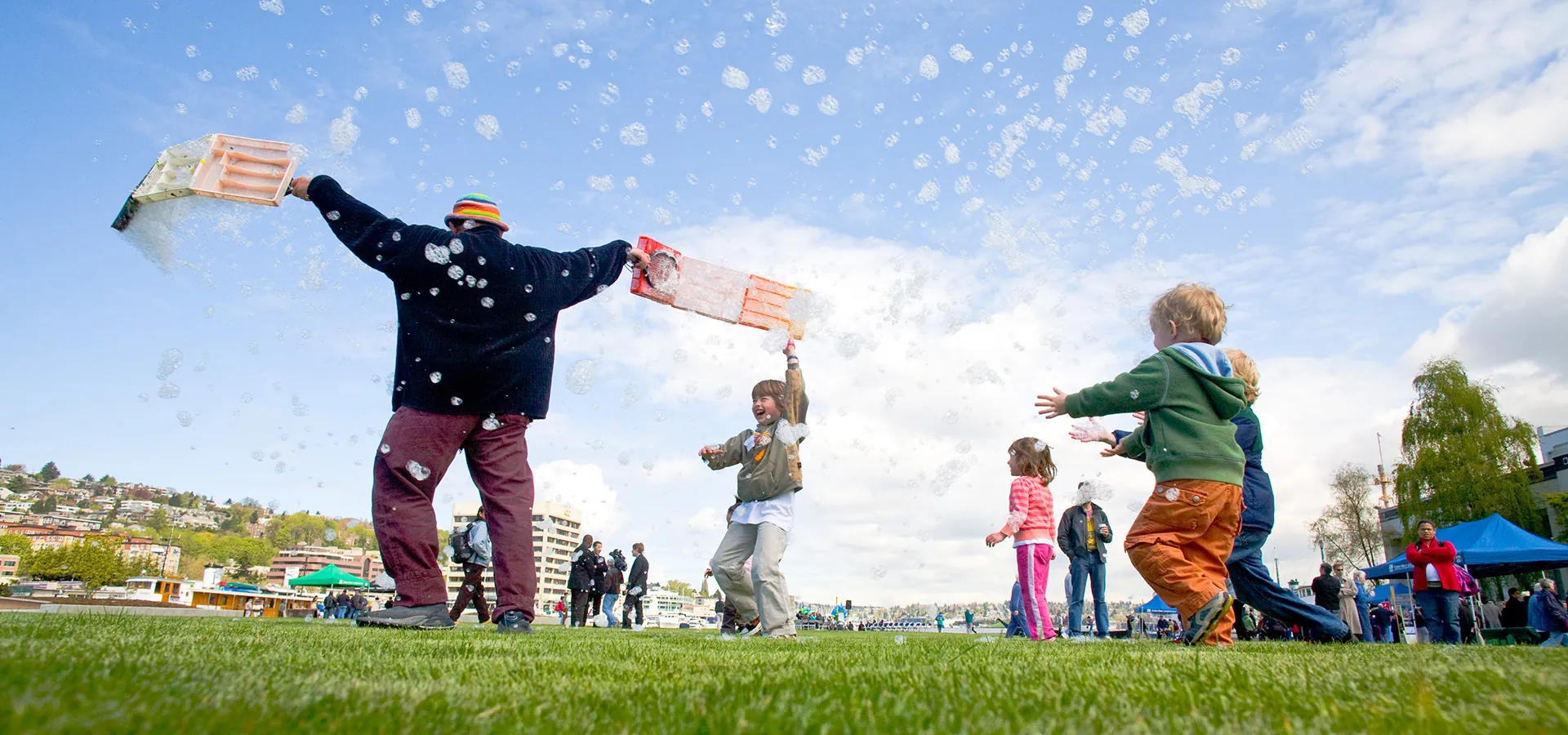 adult and children playing with bubbles in park