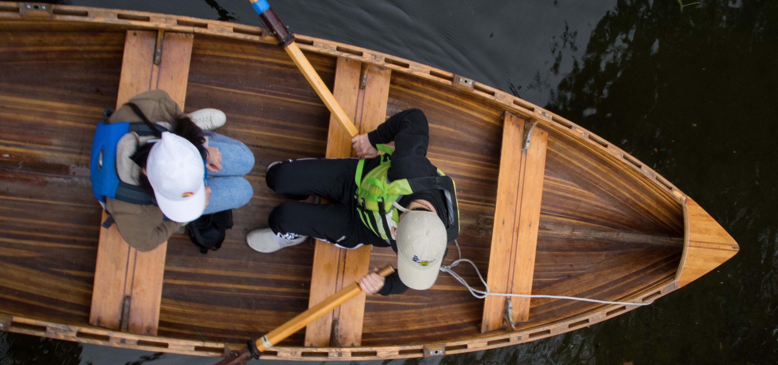 People rowing in a wooden boat.