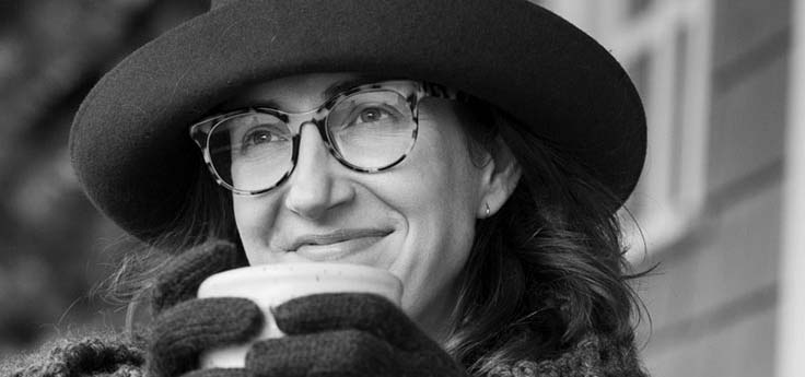 Black and white photograph of a women wearing a hat and sipping a cup of soup.