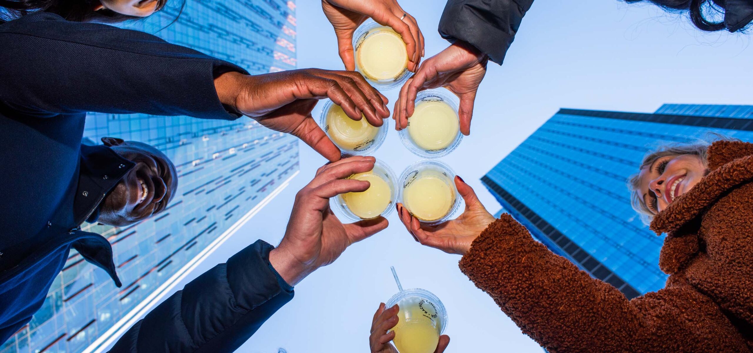 Underside view of people toasting cups of beer together.