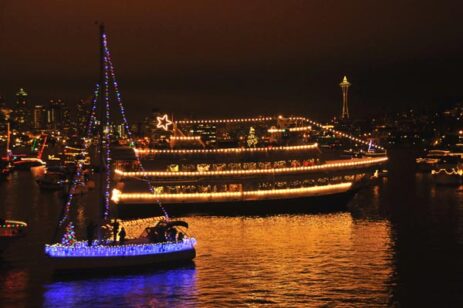 Ships sailing at night during the holidays with lights as decorations.