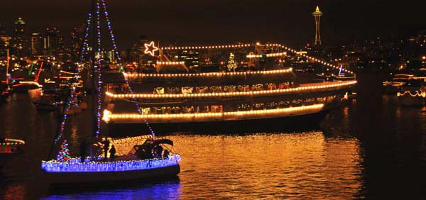 Ships sailing at night during the holidays with lights as decorations.