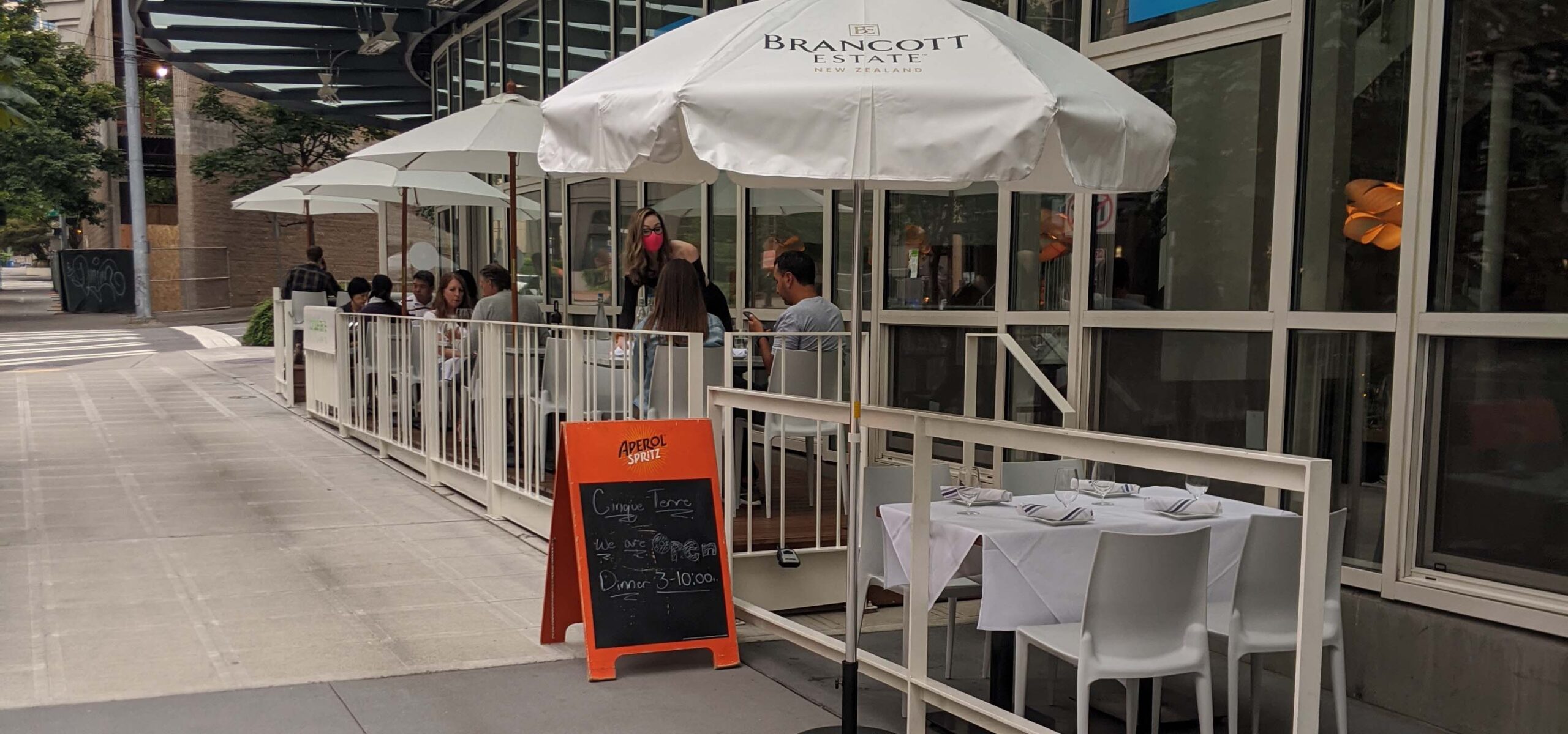 Photograph of restaurant outdoor patio with large white umbrellas over tables.