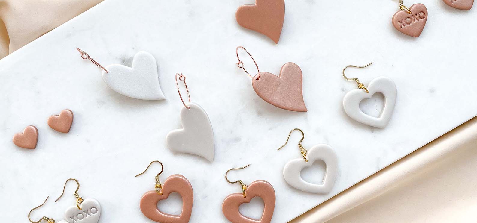 Display of heart-shaped earrings made from clay.