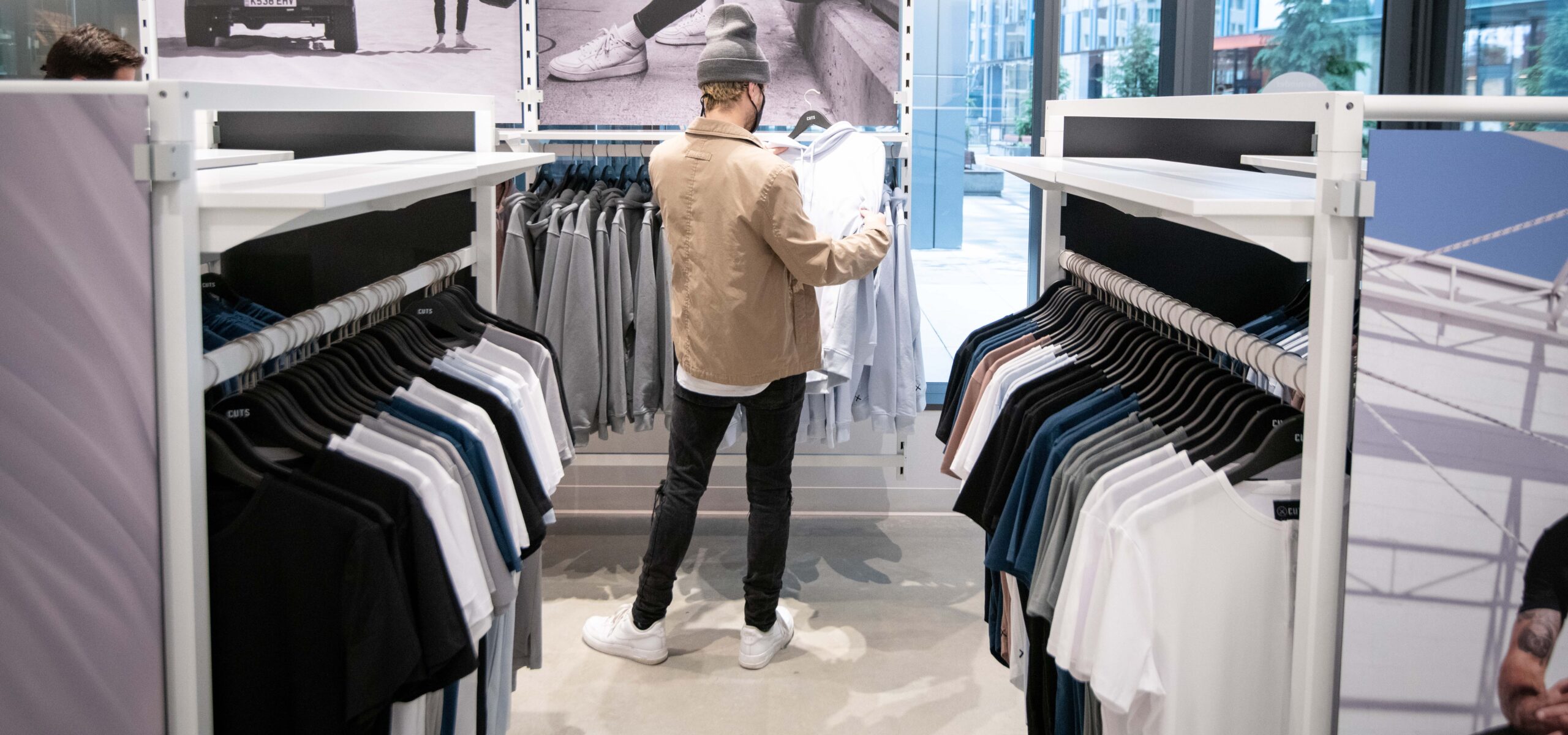 Man browsing shirts on a display rack.