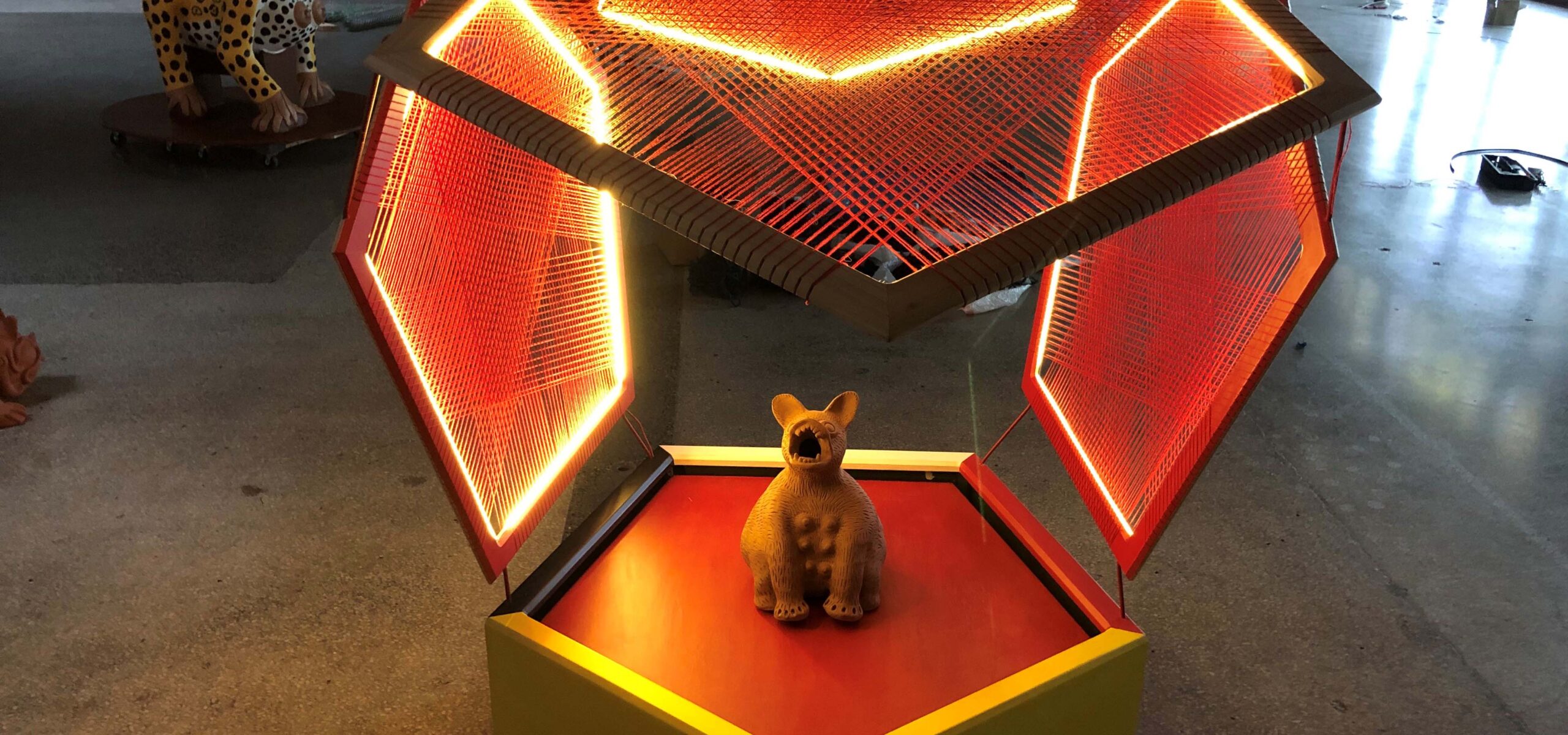 An art display with a clay figure inside a neon vessel.