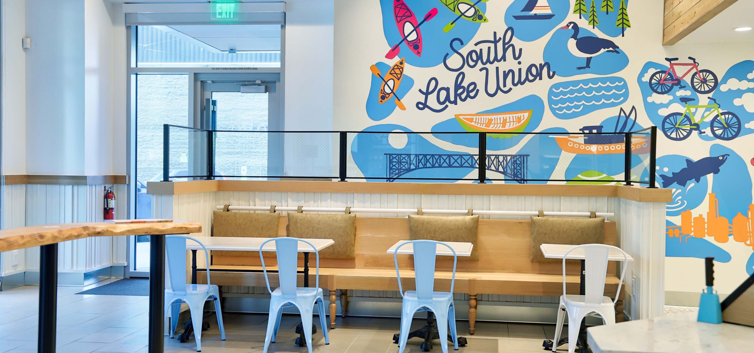 Inside a sandwich shop with a bright blue mural on the wall.