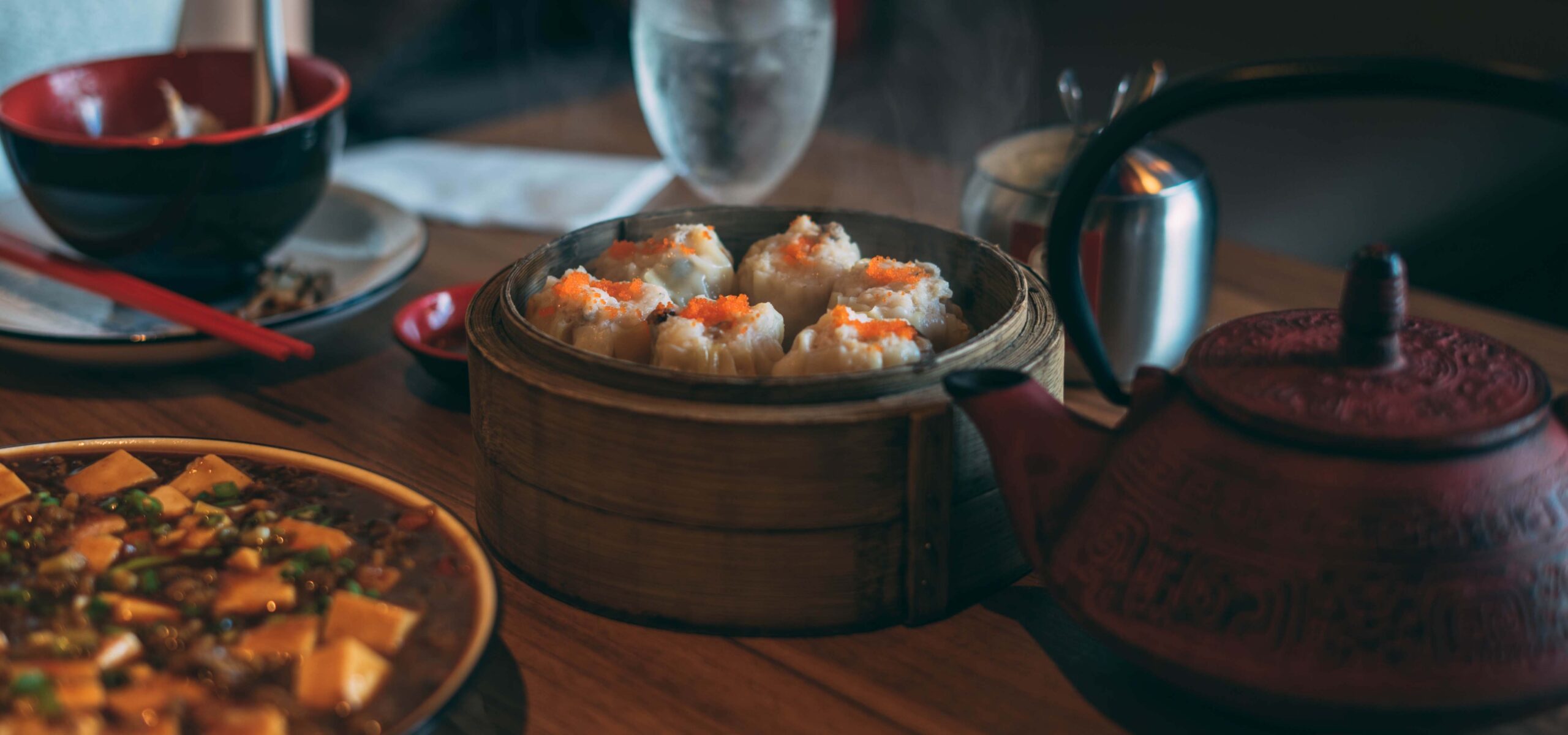 Steamer with dumplings on a table with a tea pot.