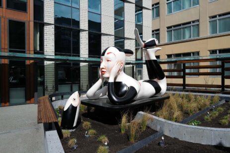 Outdoor art of a figure in a dreaming pose with a coi fish looking up at them.