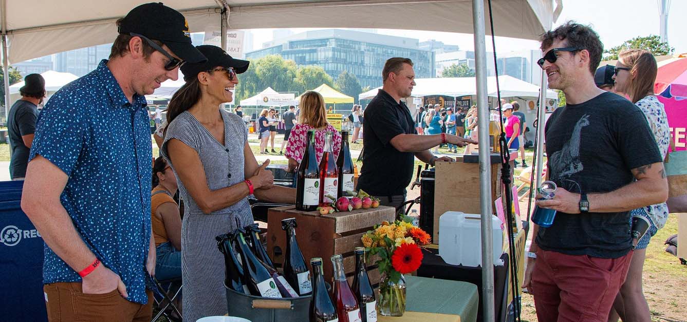 Vendors pouring cider to patrons at a festival.