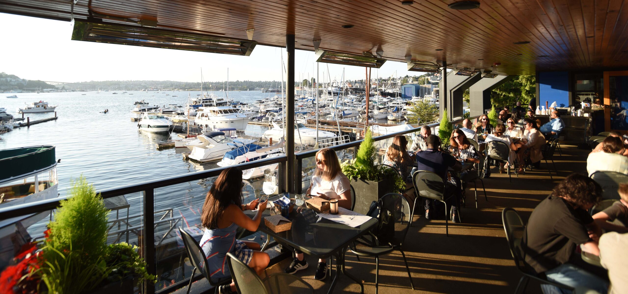 People eating on a patio by yachts.