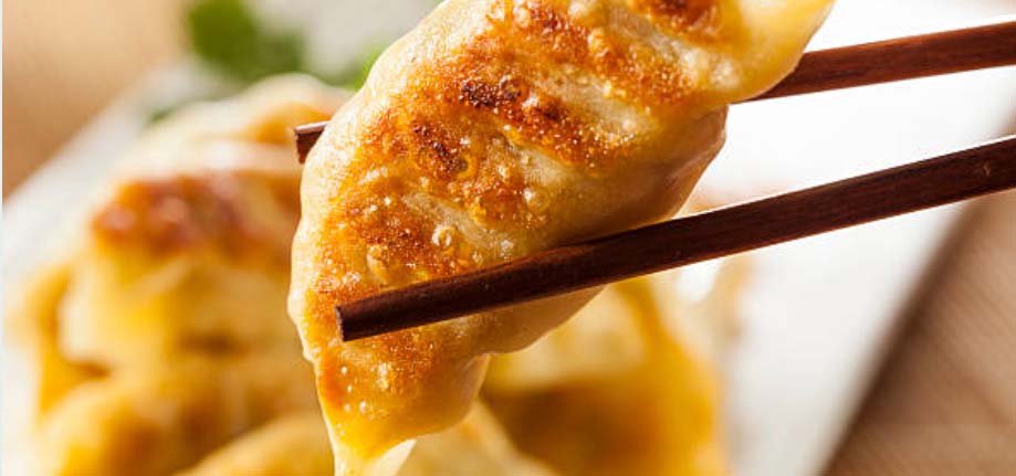 A potsticker between chop sticks.