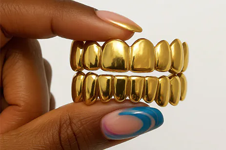 person holding gold mouth grill