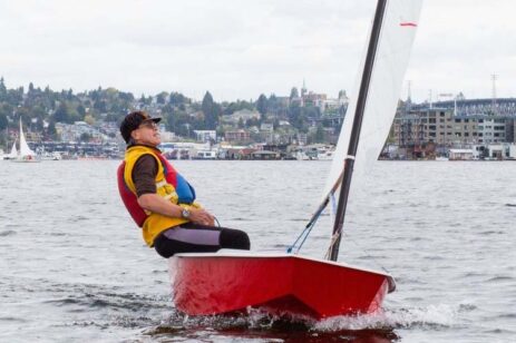 Man sailing a small red boat.