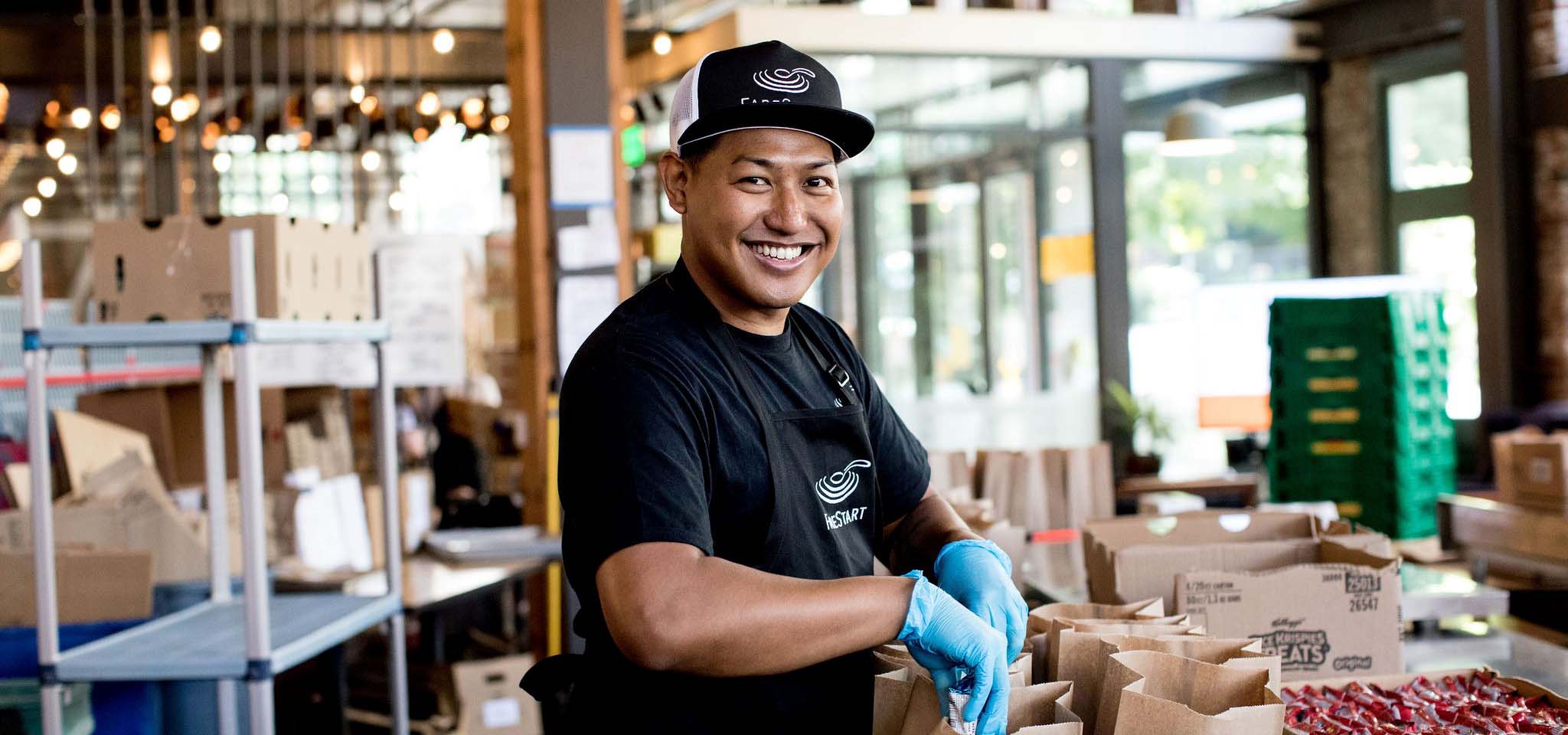 Farestart volunteer smiling while filling lunch bags.