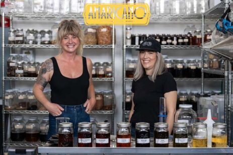 Two women in an industrial kitchen setting up for a cocktail class.