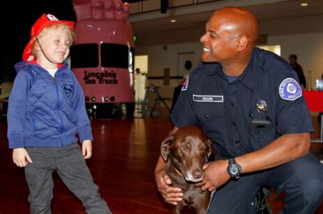 Fireman smiling at a boy in a fireman's hat.