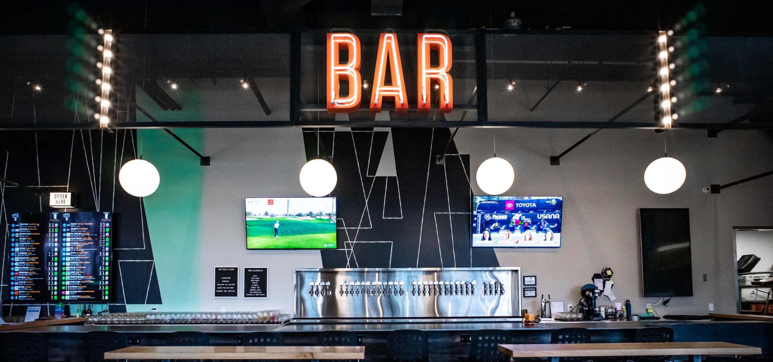 Bar counter with neon sign and TV screens above the bar.