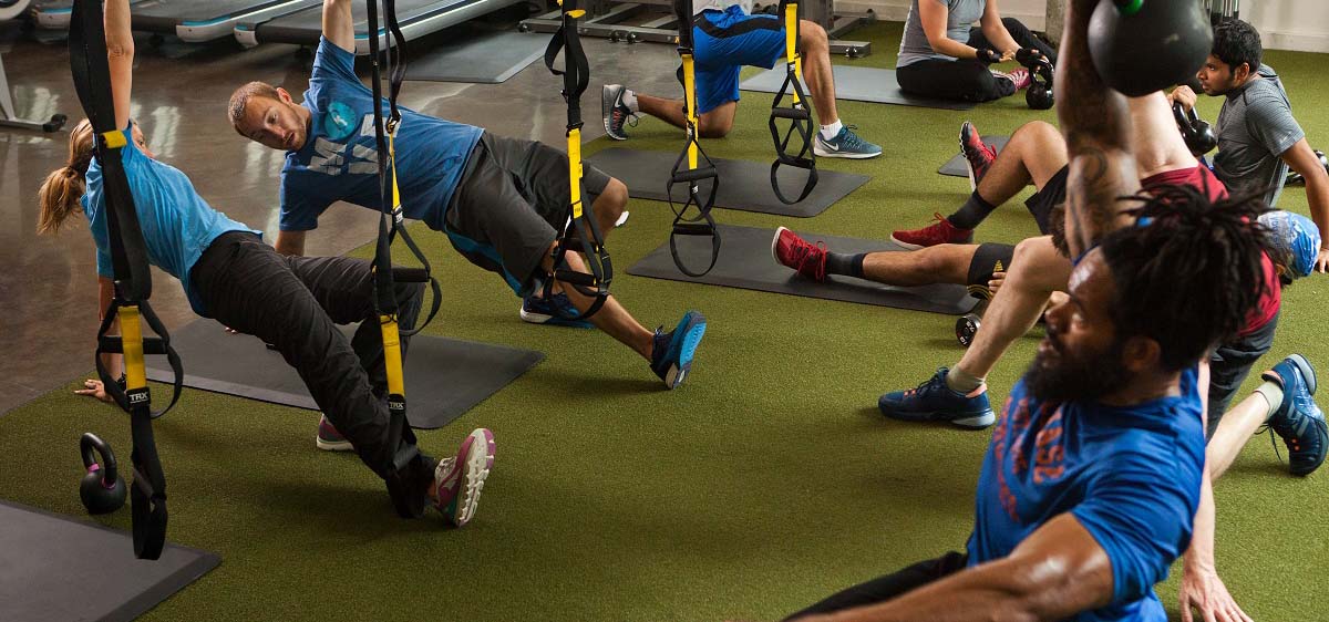 People working out in a gym on a green floor.