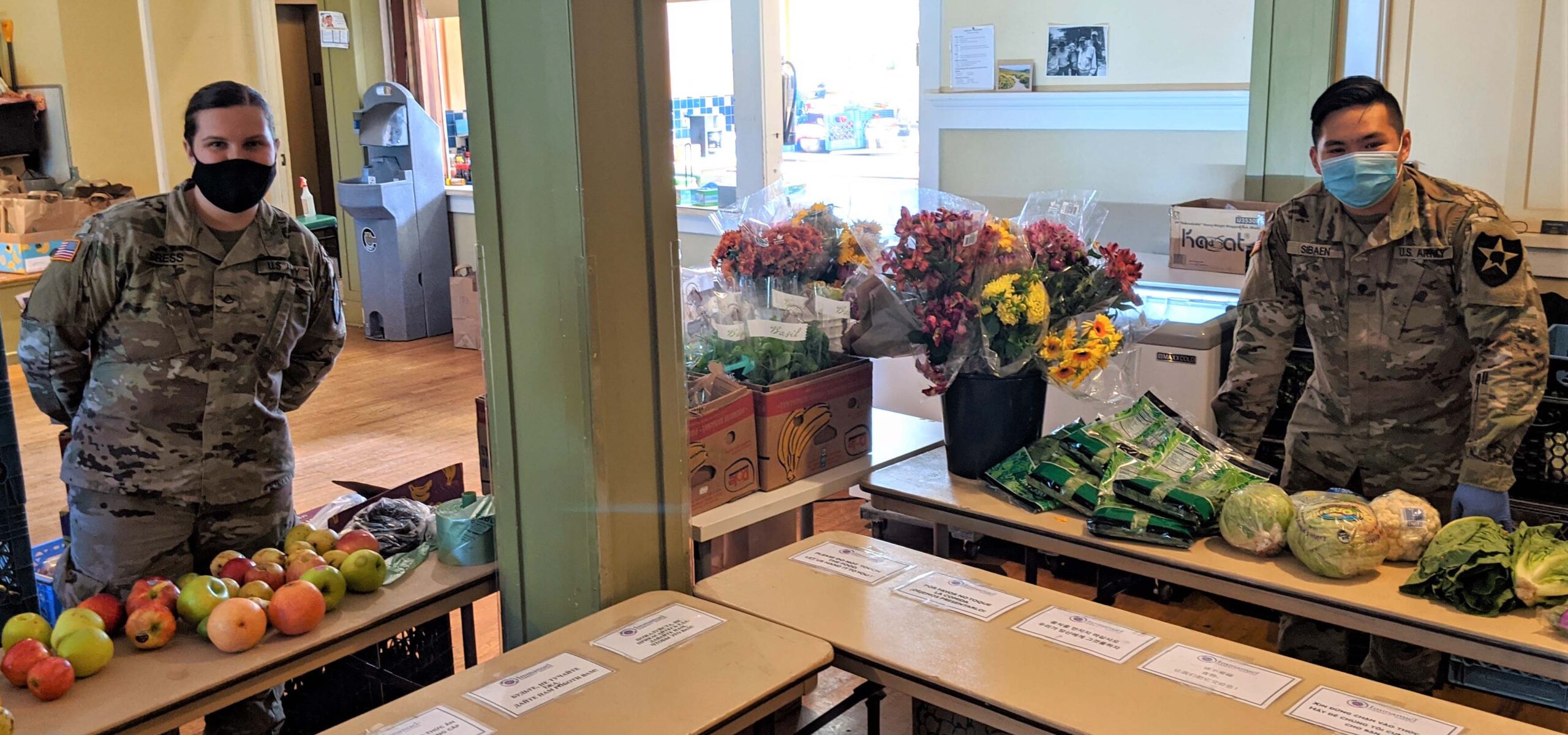 Masked volunteers sorting food donations at a shelter.