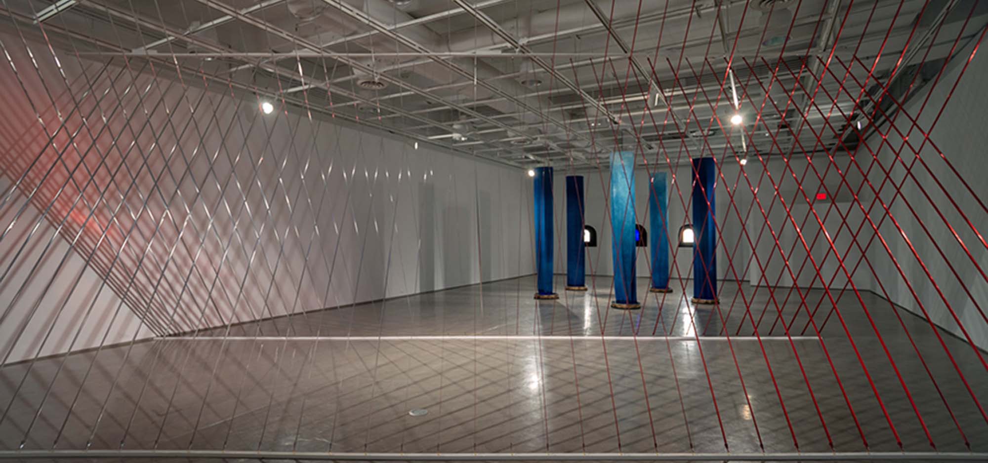 Modern art display with blue pillars and red wires.